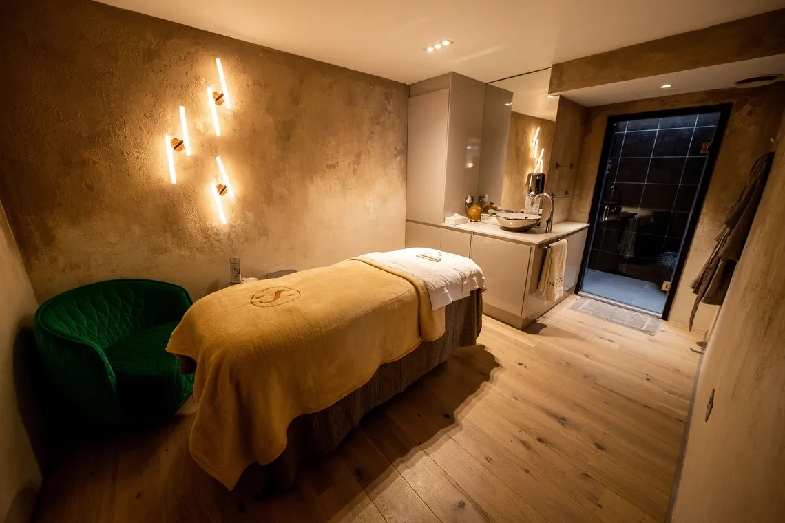 Calm beauty treatment room with neutral colours, soft towels and warm lighting